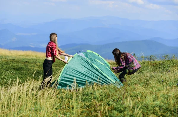 Girls set up tent on top mountain. Camping skills concept. Camping and hiking. In middle of nowhere. Temporary housing. Vacation in mountains. Camping trip. Helpful to have partner for raising tent