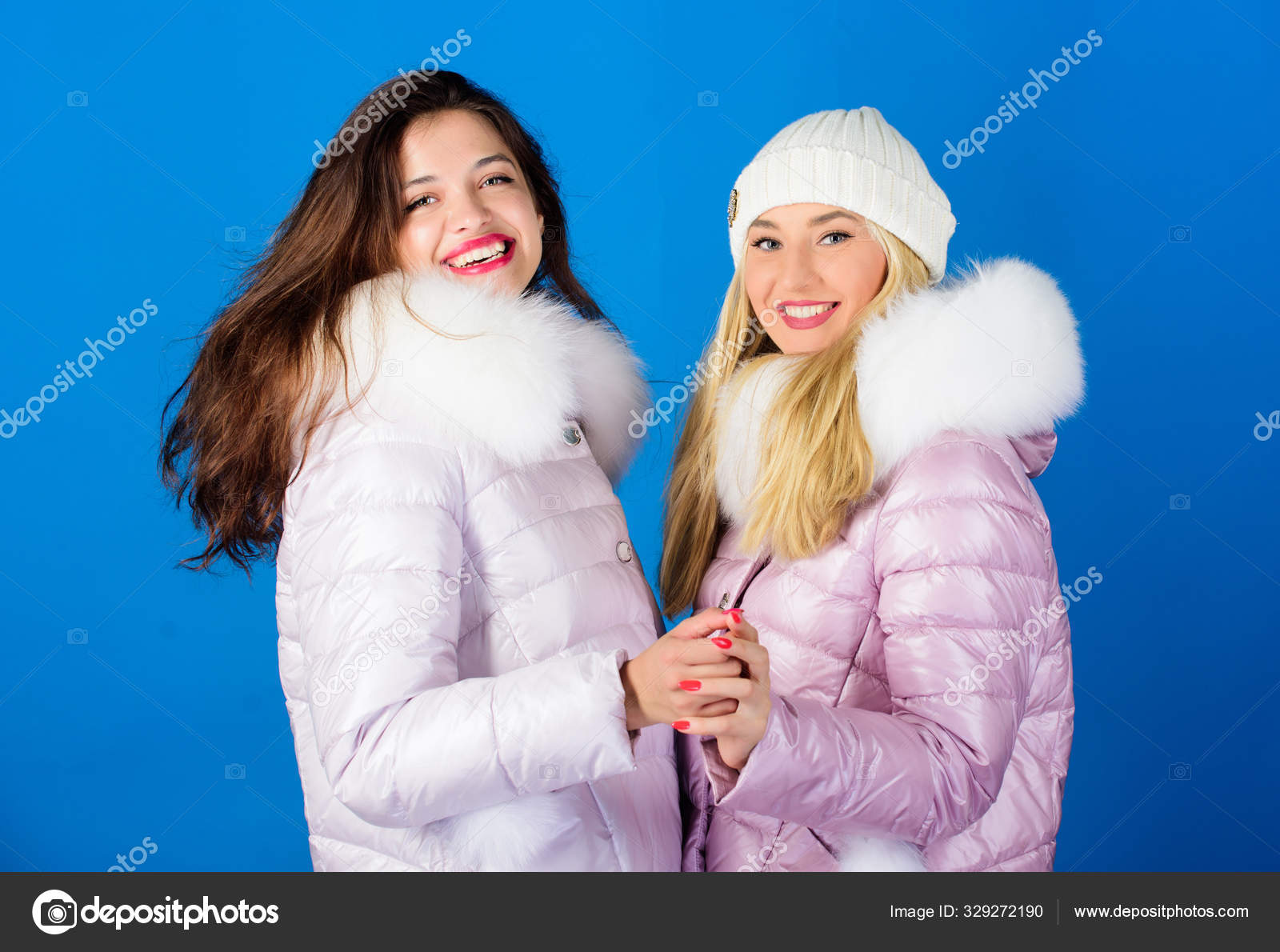 Fashion friends. Winter clothes. Women wear down jacket with furry hood.  Girls smiling makeup faces wear winter jackets blue background. Winter  season. Soft fur. For those wishing stay modern Stock Photo by ©