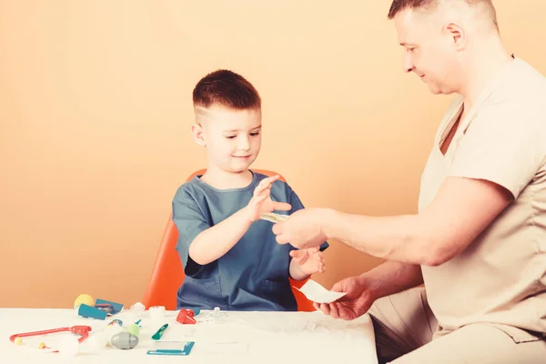 Medicina y salud. niño feliz con padre con estetoscopio. Un niño pequeño con papá en el hospital. padre e hijo en uniforme. médico de familia. confianza y valores. padre cool jugar con el niño. padre doctor —  Fotos de Stock