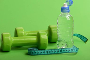 Su şişesinin yanında plastik halterler..