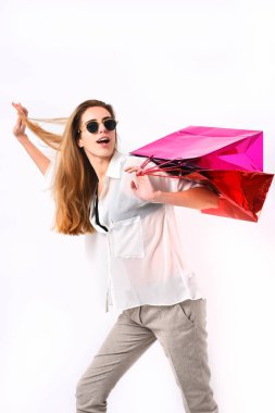 Kadının elinde kırmızı ve pembe alışveriş çantaları var..