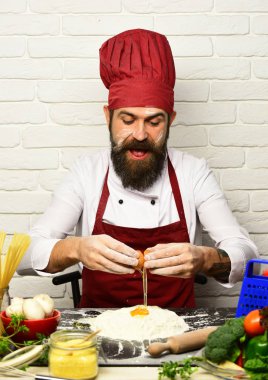 Sakallı adam beyaz arka planda yumurtayı un haline getiriyor.