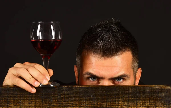 Man with beard holds glass of wine on brown background