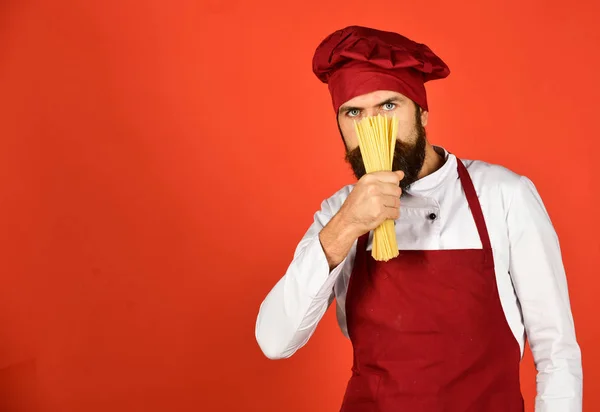 Cook with hidden serious face holds dry pasta. — Stock Photo, Image