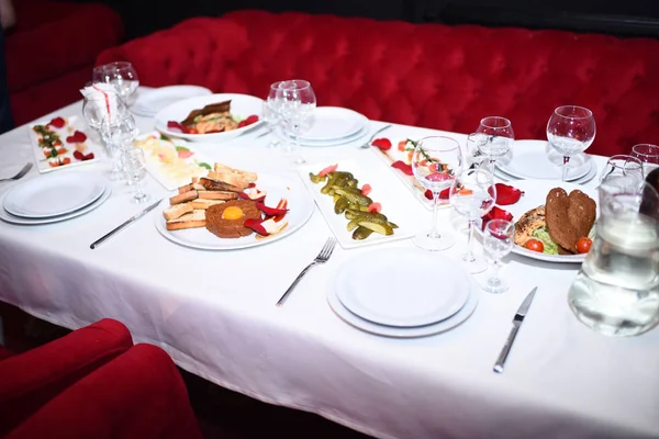 Tavolo con panno bianco vicino poltrone rosse e divano . — Foto Stock