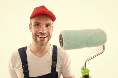 Yenileme servisi. Boya ve yenileme. Dekoratör duvar boyuyor. Şapkalı gülümseyen adam boya silindirini yakın tut. İşçi boyacı dekoratörü konsepti. Dekoratör işi. Mesleki meslek