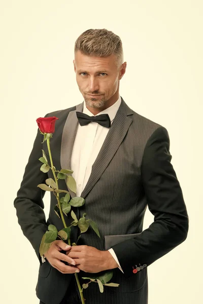 Make good first impression. Valentines day and anniversary. Romantic gentleman. Man mature confident macho with romantic gift. Handsome guy rose flower romantic date. Well groomed macho tailored suit