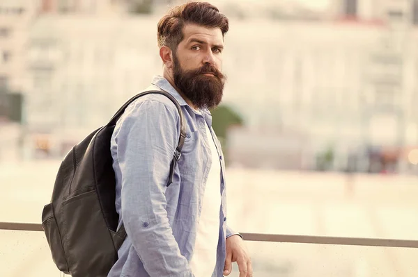 Ça a l'air plus brutal. Brutal homme caucasien à longue barbe sur fond urbain. Brutal hipster portant un sac à dos dans un style décontracté. Homme barbu avec regard brutal en plein air — Photo