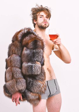 Adam çekici zengin kürk manto çıplak vücut üzerinde poz. Seksi uykulu zengin maço beyaz izole saç içki şarap tousled. Sağlık ve refah. Zenginlik ve lüks konsepti. Zengin atlet zevk hayatı