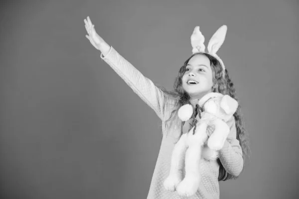 Feliz infancia. Adéntrate en el espíritu de Pascua. Accesorio de orejas de conejo. Precioso niño conejito juguetón con el pelo largo. Lindo y adorable. Conejita con lindo juguete sobre fondo azul. Niño sonriente juego conejito juguete — Foto de Stock