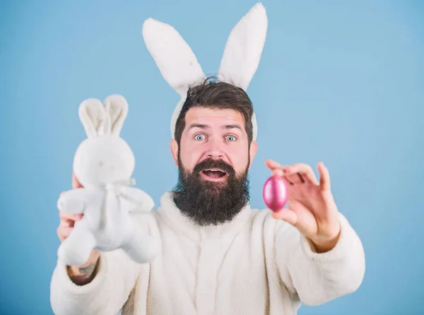 Ik ben opgewonden over Pasen. Hipster met lange konijnenoren die eieren leggen. Paashaas levert gekleurde eieren. Viering van de voorjaarsvakantie. baard man met konijn speelgoed en paaseieren — Stockfoto