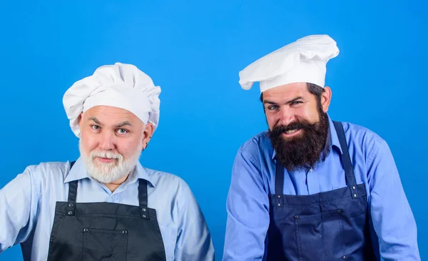 Restaurant staff. Father and son culinary hobby. Family restaurant. Mature bearded men professional restaurant cooks. Chef men wear aprons. Cafe workers. Restaurant kitchen. Culinary industry
