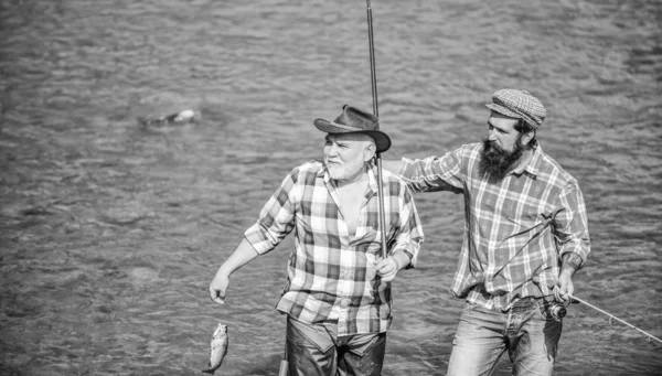 Olta ve ağ ile mutlu balıkçı. Hobi ve spor aktivitesi. Erkek arkadaşlığı. Erkekler suda durur. Güzel yakalamak kavramı. Balık tutma takımı. Baba ve oğul balık tutuyor. Yaz hafta sonu. Birlikte balıkçılık — Stok fotoğraf