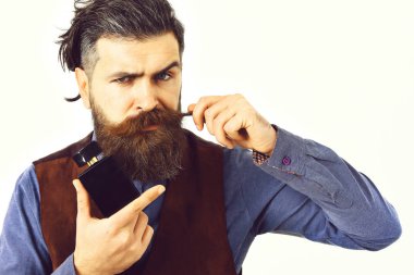 Sakallı adam ciddi bir parfüm tutuyor.