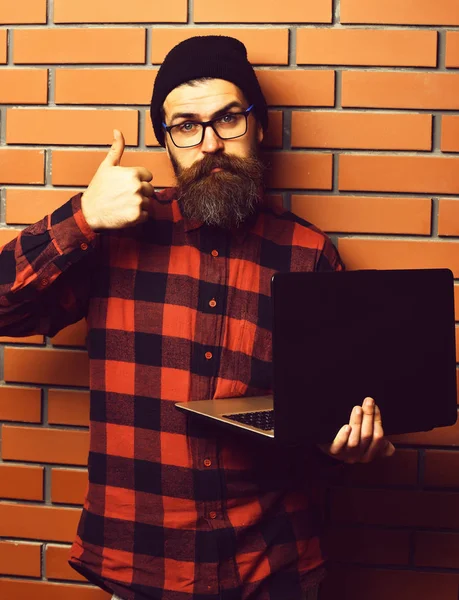 Bearded brutal caucasian hipster holding laptop — Stock Photo, Image