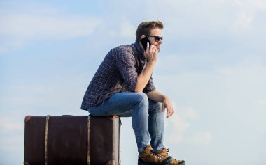 Klasik valizli bir adam. Bagaj konsepti. Taksi çağırıyorum. Seyahat acentesi. Bagajla seyahat et. Gezgin blogcu. İnsan yolculuktan önce bavula oturur. İş gezisi. Yakışıklı gezgin.