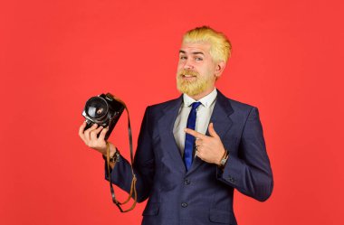 Olgun bir adam sakal ve saç boyadı. Profesyonel fotoğrafçı fotoğraf çeker. Erkek güzeli. Berber salonunun yakalanması. Klasik kamera. Kendine güvenen iş adamı retro kamerayı tutuyor