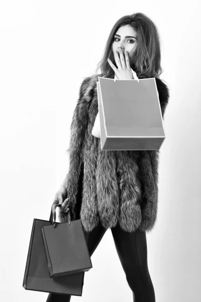 Γυναίκα εμπορικό πολυτελή μπουτίκ. Κυρία κρατούν τσάντες για ψώνια στα χέρια. Fashionista να αγοράσει μοντέρνα ρούχα σε κατάστημα. Κορίτσι μακιγιάζ προσώπου μεγάλο hairstyle φορούν γούνα γιλέκο λευκό φόντο. Ψώνια έννοια — Φωτογραφία Αρχείου