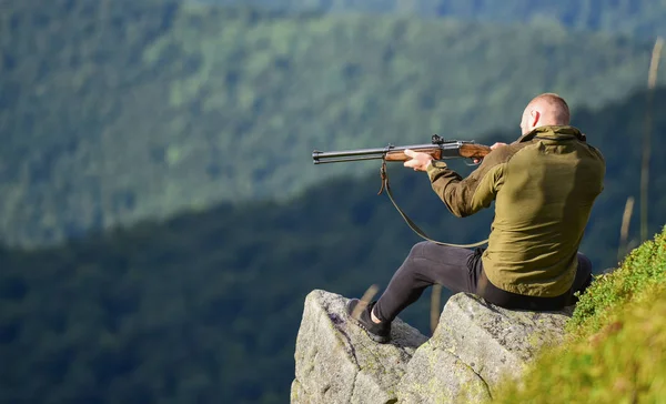 Hunter segura na espingarda. Hunter passa a caça ao lazer. Homem brutal gamekeeper natureza paisagem fundo. A caçar nas montanhas. Caçando conceito de hobby masculino. Regulação da caça. Focado no alvo — Fotografia de Stock