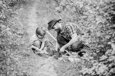 Bahar bahçe rutini. Çiçek dikiyorum. Bahçede küçük bir yardımcı. Çiftlik ailesi. Küçük çocuk ve baba doğa arka plan. Bahçe aletleri. Bahçıvanlık hobisi. Baba küçük oğlu bakım bitkileri öğretim