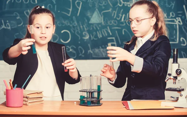 Perform chemical reactions. Basic knowledge of chemistry. Girls classmates study chemistry. Make studying chemistry interesting. Educational experiment concept. Microscope and test tubes on table