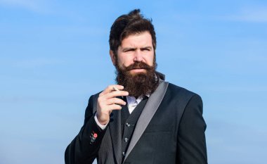 Rahatlatıcı ama zararlı bir alışkanlık. Sakallı ve bıyıklı bir adam sigara tutuyor. Sigara içen sakallı hippi. Sigaralı adam nikotin etkisinden hoşlanır. Sigara içmenin zevki