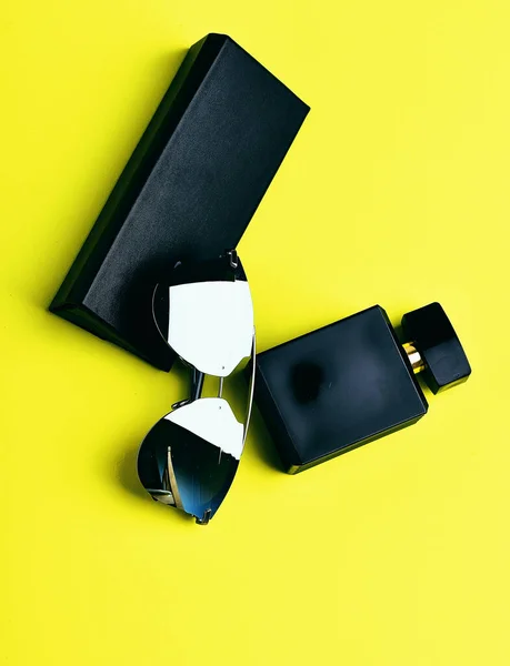 Zenske zrcadlové sluneční brýle, parfémy a případ na žlutém podkladu — Stock fotografie