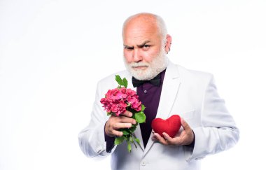 Yakışıklı sakallı adam smokin giyer. Romantizm ve flört. Yaşlı centilmen romantik ruh. Adam sevginin kalp sembolünü taşıyor. Yaşlılar için flört hizmetleri. Centilmen kavramı. Gerçek beyefendi.