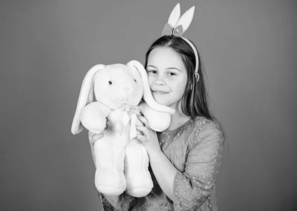 Bunny oren accessoire. Mooie speelse bunny kind hugs zacht stuk speelgoed. Bunny meisje met leuk speelgoed op blauwe achtergrond. Lachende spelen bunny speelgoed kind. Heb gezegend Pasen. Krijgen in de geest van de Pasen. Gelukkige jeugd — Stockfoto