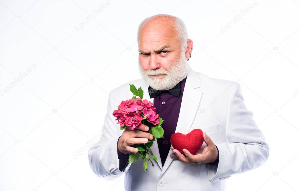 Well groomed handsome bearded man wear tuxedo. Romance and dating. Senior gentleman romantic soul. Man hold heart symbol of love. Dating services for elderly people. Gentleman concept. True gentleman