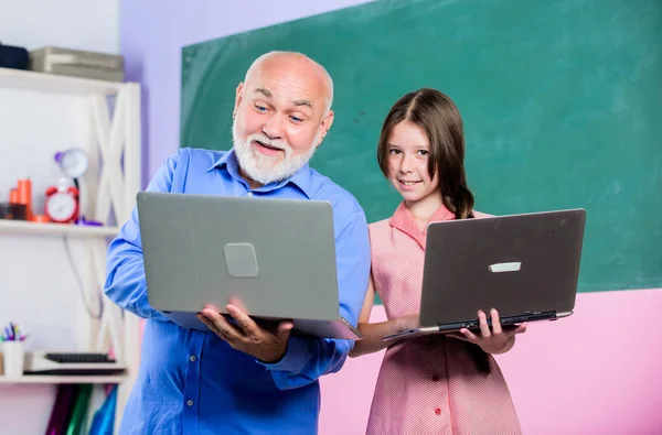 回学校去在线课程。数字科学教师。老师帮助学校的女孩。带着男老师学习的小女孩拿着笔记本电脑。教孩子的互联网课程。现代学校。现代教育家 — 图库照片