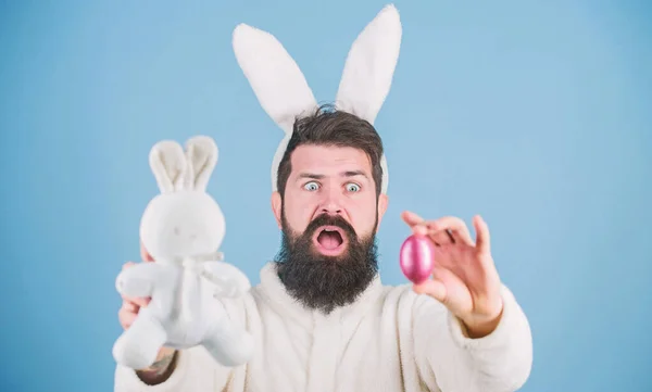 Бородатий чоловік носить вуха кролика. Полювання на яйце. Подивіться, що я знайшов. Хіпстер милий кролик синій фон. Великодній кролик. Мій дорогоцінний. Веселий кролик з бородою і вусами тримає рожеве яйце. концепція великоднього символу — стокове фото
