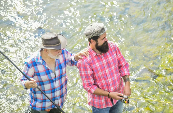 ファッションをチェック釣り竿と網を持った漁師です湖の岸にキャンプ。父と息子の釣り密猟だ田舎の休暇の概念です趣味だ野生の自然大きなゲーム釣り。友情 — ストック写真
