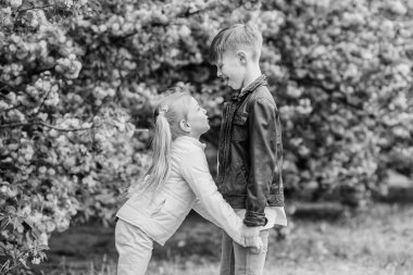 Havada aşk var. Çift sevimli sevimli çocuklar sakura bahçe yürümek. Şefkatli aşk duyguları. Küçük kız ve oğlan. Parkta romantik bir randevu. Aşık olmak için bahar zamanı. Aşık çocuklar pembe kiraz çiçeği