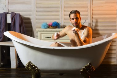 Küvet içinde köpük ile oynarken maço. Adam banyoda