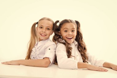 Birinci sınıf. Mutlu çocukluk. Sevimli kız öğrenciler. Okula geri dön. Eğitim kavramı. Güzel kızlar en iyi arkadaşlar. Resmi tarz. Kız öğrenciler masa beyaz arka plan oturup. Schoolgirls duygusal arkadaşlar