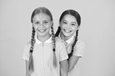 Güzel kız öğrenciler. Okul konseptine geri dönelim. Sevimli kız öğrenciler. Örgülü saç stili olan kızlar. Kuaför salonu. Neşeli kız öğrenciler sarı arka plan. Sevimli örgüler ile oynayan küçük kızlar