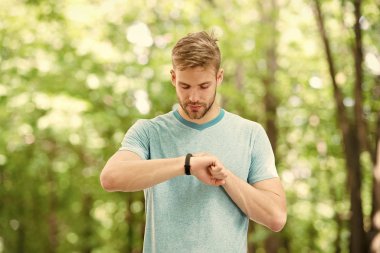 Kalori sayıyorum. Bilek bandı aleti. Atlet kontrol fitness izci doğa arka plan. Kıllı atlet pedometre gadget ilerleme sonucu bakar. Akıllı saat gadget ile sporcu eğitimi