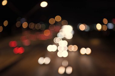 Gece şehir ışıkları. Aydınlatma ve aydınlatma. Beyaz ve kırmızı bulanık lambalar. Ulaşımın sokakta hareket inişini izliyorum. Şehir trafiği. Bulanık araba ışıkları gece. Şehir gecesi. Işıklar deodaklanmış arka plan