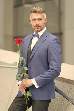 Bakımlı maço takım elbise. İyi bir ilk izlenim bırak. Sevgililer günü ve yıldönümü. Romantik bir beyefendi. Romantik hediye ile adam olgun kendinden emin maço. Yakışıklı adam gül çiçek romantik tarih