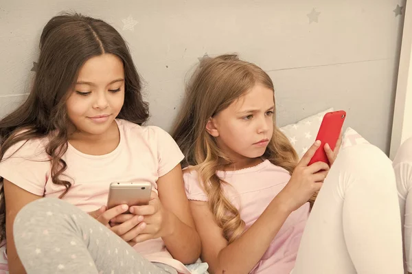 Online zijn. Praten voor het slapen gaan. beste vrienden. Zusters gebruiken telefoon in bed. Slaap lekker. pyjamafeest in de slaapkamer. kindertijd met nieuwe technologie. surfen op internet. Kinderen zijn aan het bloggen. ochtendvibes — Stockfoto