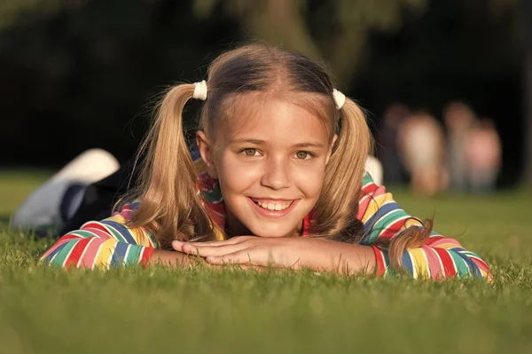 I miei capelli il mio sguardo. Bambino felice con sguardo di bellezza rilassarsi sull'erba verde. Vogue sguardo di piccolo modello di moda. Adorabile sorriso ragazza con sguardo di moda il giorno d'estate — Foto Stock