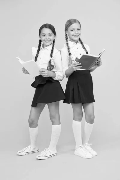 Día del conocimiento. Día escolar. Amistad escolar. Chica con libros de texto o libros de trabajo. Estudien juntos. Niños lindos estudiantes. Colegialas mejores amigos excelentes alumnos. Las colegialas usan uniforme escolar — Foto de Stock