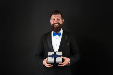 Tatili mükemmel bir hediyeyle kutlayın. Şimdiki mutlu iş adamı. Sakallı adam hediye kutusunu tutuyor. Hediye alışverişi. Hediyelik eşya dükkanı. Kutlama ve hazırlık. Hatıra olarak. Vermenin sevinci