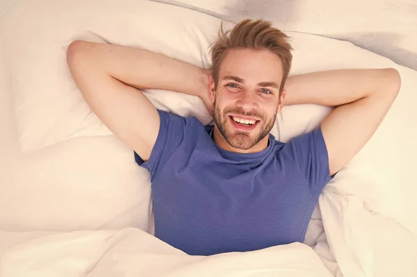 New smile, new day. Happy man awaken in bed. Handsome caucasian man with happy smile relaxing in the morning. Sparkling white smile treatment and aftercare procedure. Smile that fits his lifestyle