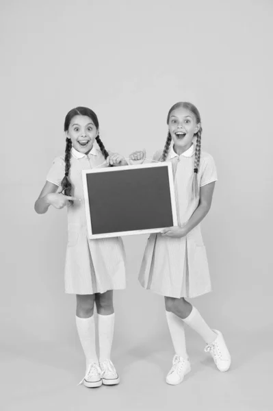 Betygsskala. Vintage mode. tillbaka till skolan. små flickor håller Blackboard. barnuppfostran. flickor som presenterar information. gamla skolan. Kopiera utrymme ombord. förvånade vänner i retro Uniform — Stockfoto