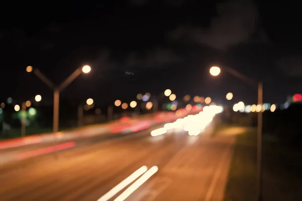 Viendo el transporte moviéndose en la calle. Tráfico urbano. Noche de luces borrosas del coche. Noche urbana. Luces desenfocadas. Luces nocturnas. Iluminación e iluminación. Lámparas borrosas blancas y rojas —  Fotos de Stock