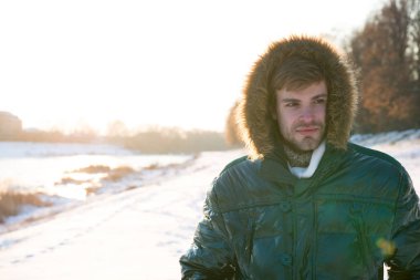 Kış kıyafeti. Hipster moda kıyafeti. Erkek ceketi. Sıcak ceketli, karlı bir arka plan. Rüzgara dayanıklı kıyafetler. Kış havası. Kutup kaşifi. Güneşli kış günü. Kış erkek giyimi