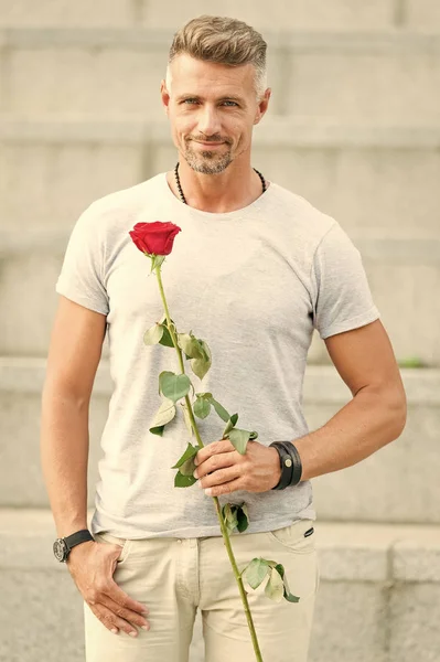 Το ειδύλλιο μπορεί να ενισχύσει την ερωτική σου ζωή. Όμορφος τύπος με ροζ λουλούδι ρομαντικό ραντεβού. Ημέρα του Αγίου Βαλεντίνου και επέτειος. Παράδοση λουλουδιών. Ρομαντικός κύριος. Άντρας ώριμο μάτσο με ρομαντικό δώρο — Φωτογραφία Αρχείου