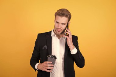 Haberleri sunuyorum. Kahve içen adam telefonla sarı arka planda konuşuyor. Kahve iç. Girişimciler kahve içebilirler. Kahve molası. Rahatla ve zevk al. Dinleme bilgilerine odaklan